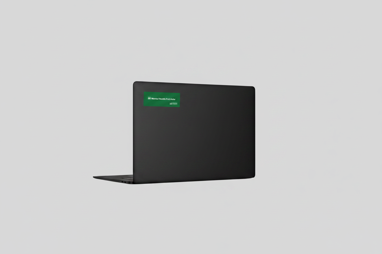 A white laptop shown closed from the back, featuring a small green rectangular sticker with white text near the top right of the lid, set against a solid light gray background.