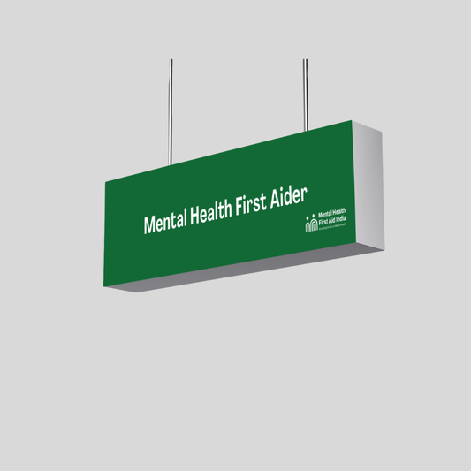 A rectangular green hanging sign with white text reading 'Mental Health First Aider' and a small Mental Health First Aider logo on the lower right, shown against a light gray background.