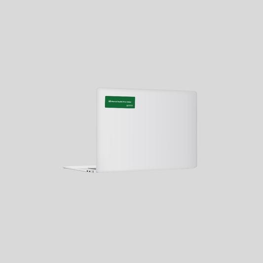 A white laptop shown closed from the back, featuring a small green rectangular sticker with white text near the top right of the lid, set against a solid light gray background.