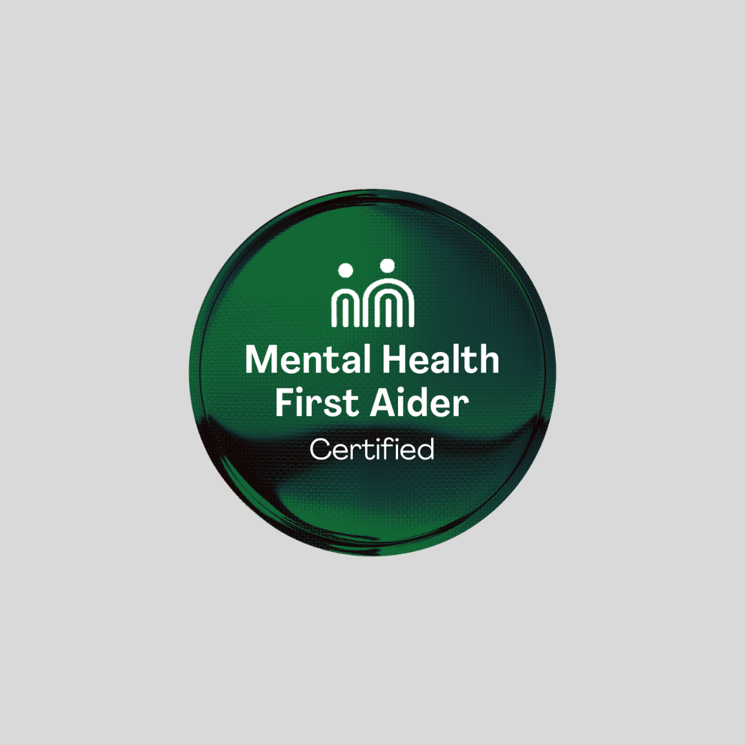 A circular green badge with white text reading 'Mental Health First Aider Certified' and a simple white icon above, centered on a light gray background.